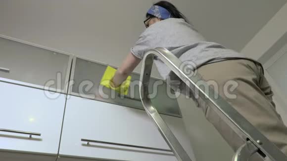 在楼梯上打扫厨房家具的女人视频的预览图