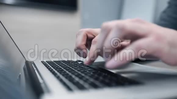 穿灰色套头衫的人用他的笔记本工作人手在键盘上打字人用笔记本把手合上视频的预览图