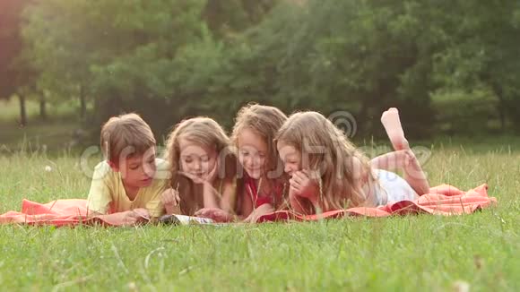 男孩和女孩在躺在毯子上的花园里笑着读了一本书慢动作关门视频的预览图