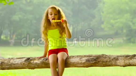 迷人的女孩在夏天的花园里玩肥皂泡背景模糊慢动作视频的预览图