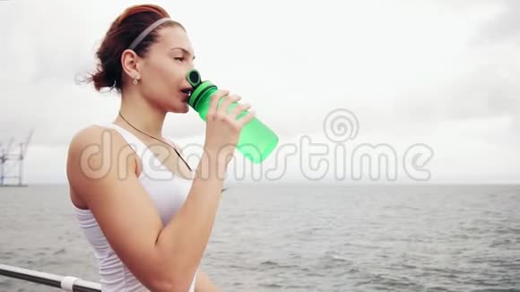 口渴的健身妇女休息休息与水瓶饮用后训练美丽的女子训练视频的预览图
