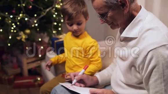 积极的老人和他的小孙子在圣诞卡上签名视频的预览图