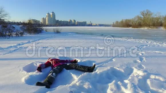 快乐的小女孩躺在城市公园的雪地上玩雪寒假快乐视频的预览图
