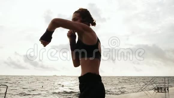 一位年轻女子的影子拳击特写镜头她的双手裹着紫色的拳击磁带靠在海边晒太阳视频的预览图