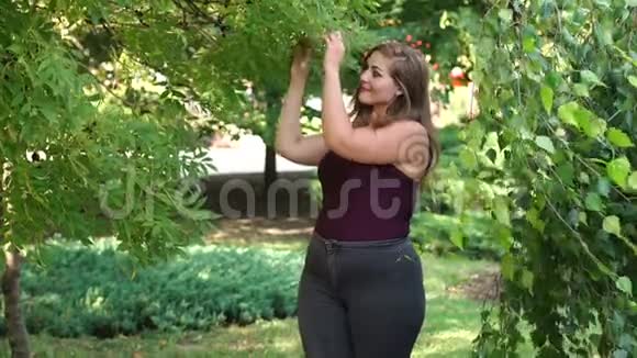 一个体重超标的年轻女孩在绿树丛中散步视频的预览图