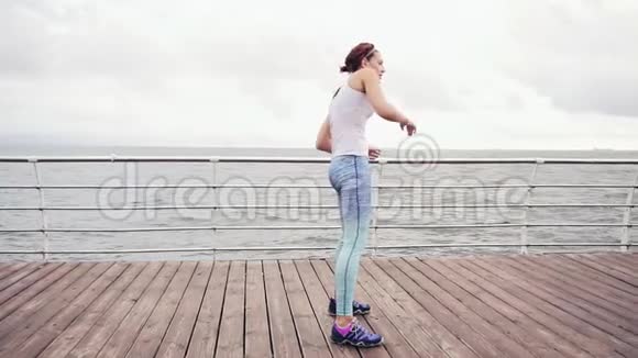 运动的年轻女子在海边的海滩上做后弯和伸展运动慢镜头视频的预览图