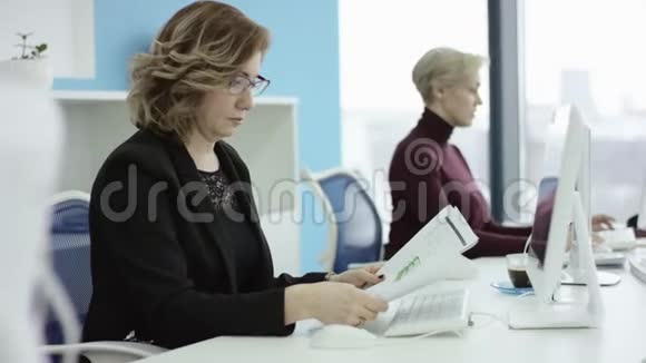 有魅力的年轻女商人在办公室通过电脑工作特写时髦的学生女孩浏览视频的预览图
