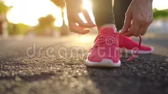 在日落时分女人系鞋带沿着棕榈大道奔跑慢动作视频的预览图