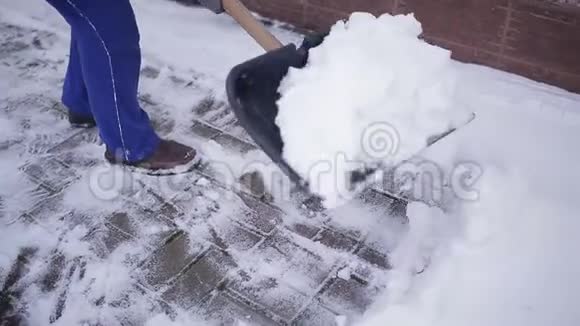 一位老妇人在一院子的雪堆里打扫铲子视频的预览图