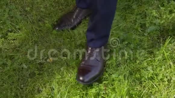穿着裤子的人和穿着棕色靴子在草地上走得很近视频的预览图