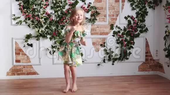 穿着绿色裙子的金发女孩光着脚玩跳舞跳跃旋转视频的预览图