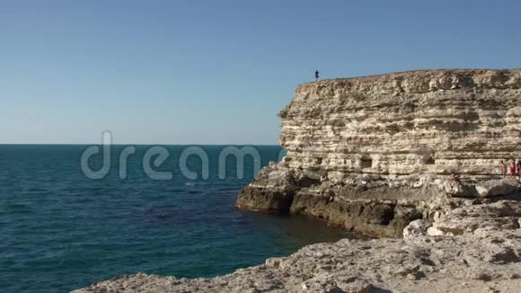在海面上的一块岩石上的一个小女人视频的预览图