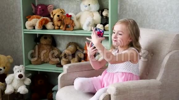 小女孩在家里用手机拍自拍照片视频的预览图