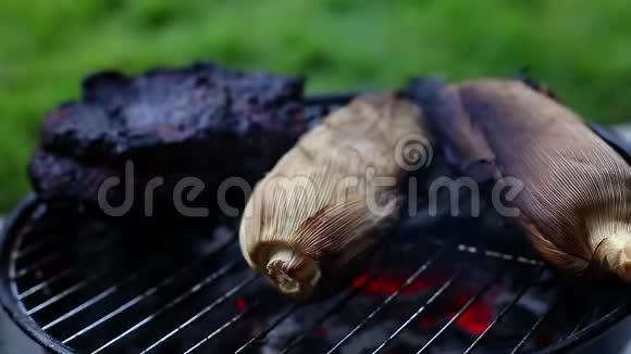 一个巨大的牛腩和玉米在一个小的木炭烤架上烤着里面有燃烧的煤视频的预览图