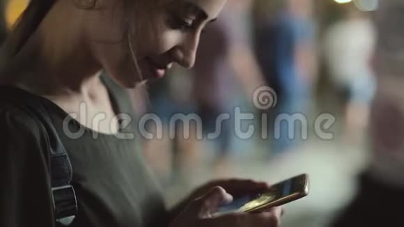 年轻女子晚上在城市里用电话站在户外视频的预览图
