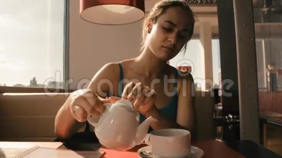 咖啡馆里的女孩把茶倒进杯子里视频的预览图