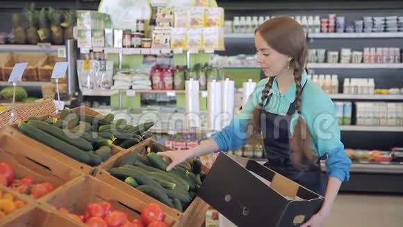 商人把温室黄瓜超市放在蔬菜部门的盒子里两条辫子的女人视频的预览图