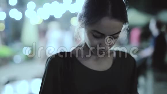 年轻女子晚上在城市里用电话站在户外视频的预览图