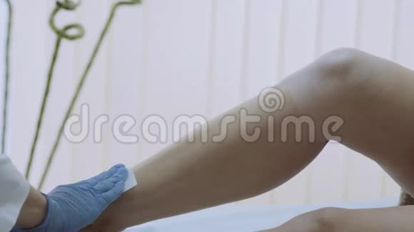 美容师给一个女人腿上打蜡在腿上涂上一种热的材料痛苦的过程视频的预览图
