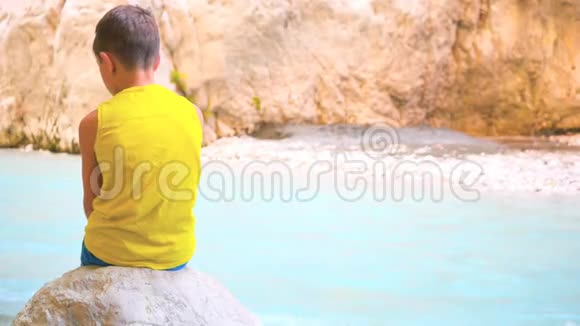 儿童坐在石头上的后景视频的预览图