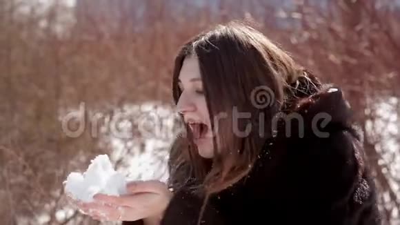 戴着眼镜和貂皮大衣的快乐女孩把手里的雪吹得通红视频的预览图