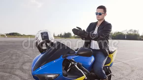 骑摩托车的人戴着特制的皮制手套戴着墨镜和皮夹克坐在摩托车上视频的预览图