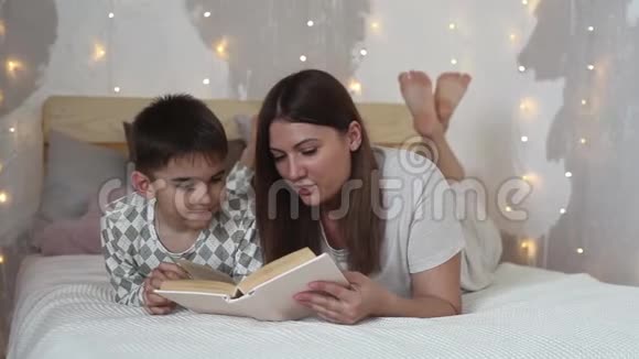 一个留着长发的漂亮女孩给躺在床上的小男孩读了一本书然后吻了他视频的预览图
