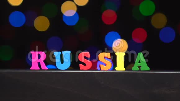 色彩斑斓的文字俄罗斯由多种色彩的木制字母在抽象模糊的灯光前背景视频的预览图