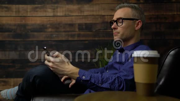 坐在软椅上的男人用电话喝咖啡视频的预览图