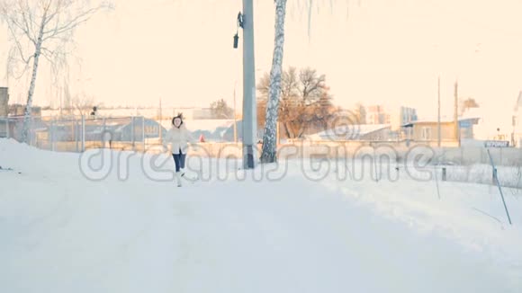 穿着白大褂的卷发女孩在冬季公园里慢镜头地跑到镜头前视频的预览图