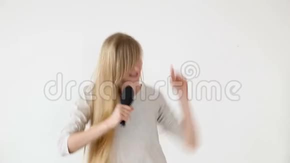 开朗迷人的少女唱着歌像麦克风一样举着梳子在白色的背景上视频的预览图