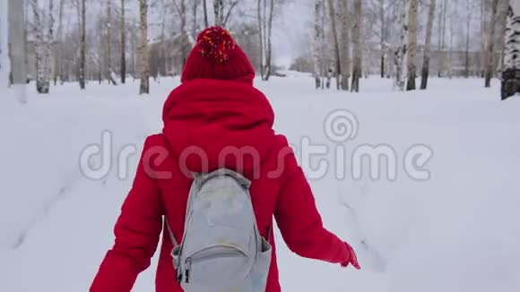 穿着红色夹克衫头罩走路的女孩在雪地里独自行走视频的预览图