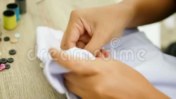 一个女人在白色衬衫上缝一个红色标志时要紧紧抓住她的手视频的预览图