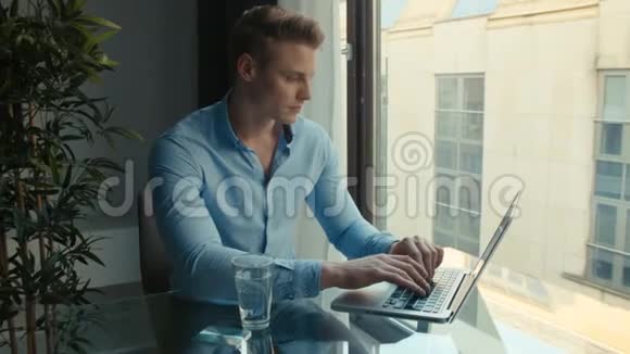 英俊的年轻人在室内用笔记本电脑工作视频的预览图