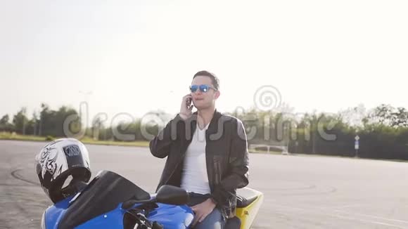 一个年轻人坐在他的摩托车上在电话里聊得很开心视频的预览图