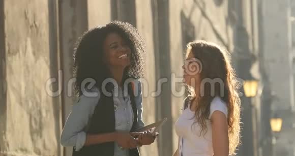 两个迷人的微笑学生在街上有趣的交谈那个女孩正在纠正头发视频的预览图
