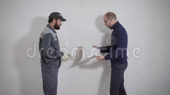 顾客和修理工站在一个白色墙壁背景的公寓里业主正在解释该怎么做视频的预览图