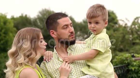 绿树背景下幸福家庭和一个小孩子的肖像视频的预览图