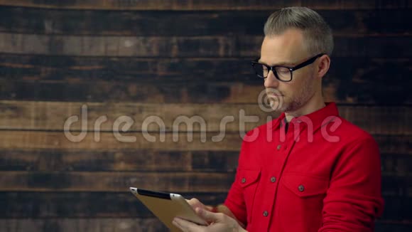 穿红色衬衫的时髦男人用平板微笑视频的预览图