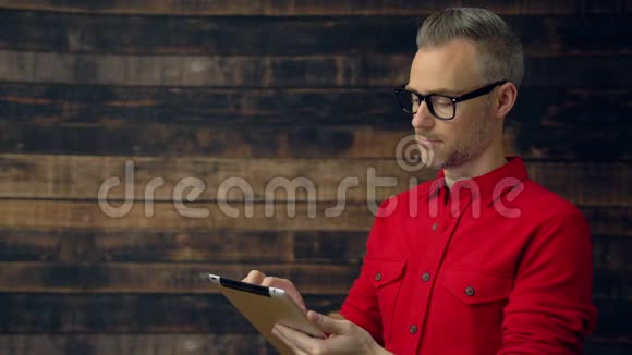 穿红色衬衫的时髦男人中间用平板电脑视频的预览图