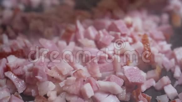 一个用木铲搅拌的厨师把切碎的熏肉用热煎锅煎炸视频的预览图
