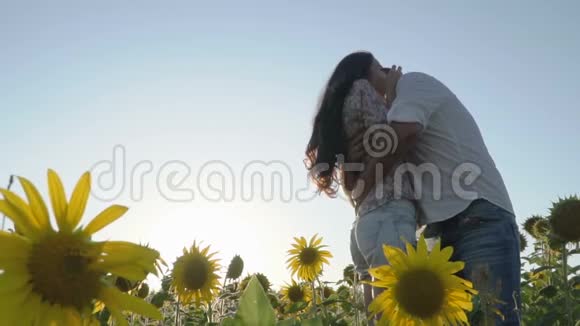 恋爱中的夫妻幸福地站在向日葵的田野上视频的预览图