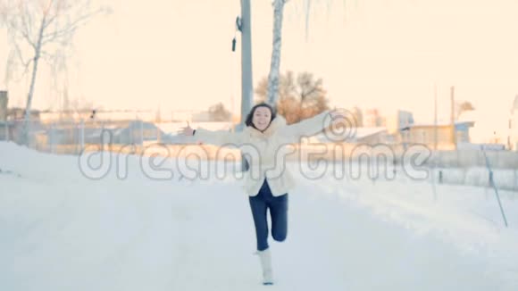 快乐的女人在雪地公园里慢镜头地奔跑视频的预览图