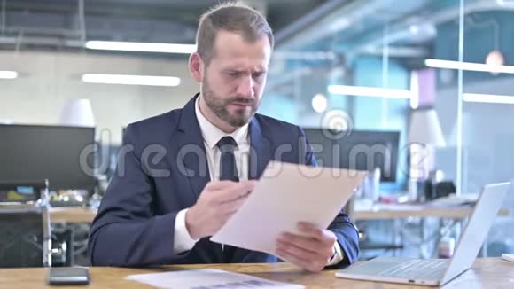 扰乱年轻商人在办公室阅读文件视频的预览图