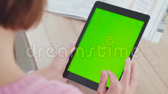 年轻女性使用的平板电脑有绿色屏幕滚动触摸它视频的预览图