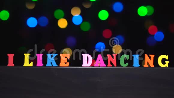 色彩斑斓的文字我喜欢在抽象模糊的灯光背景下用多种颜色的木制字母跳舞视频的预览图