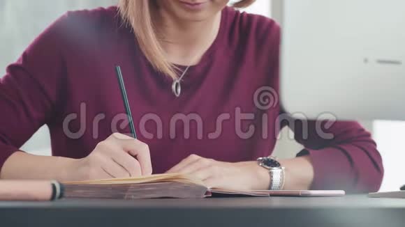 一个在明亮办公室的女人在日记里写一周的计划视频的预览图