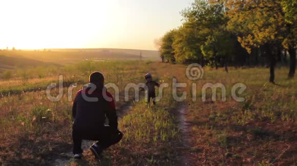 快乐的孩子在日落时分森林里跑进他父亲的怀里视频的预览图