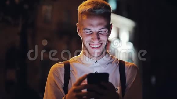 年轻有魅力的男人用智能手机站在夜城的街道上交流旅游旅游约会商务视频的预览图