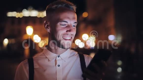 年轻有魅力的男人用智能手机站在夜城的街道上交流旅游旅游约会商务视频的预览图